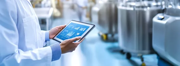 Scientist using a tablet to monitor data in a modern pharmaceutical or chemical manufacturing facility