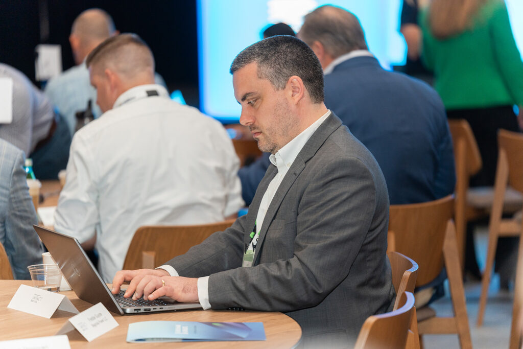 Sustainability executive seated in front of a laptop at Benchmark Gensuite's 2025 Impact conference for subscribers