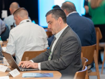 Sustainability executive seated in front of a laptop at Benchmark Gensuite's 2025 Impact conference for subscribers