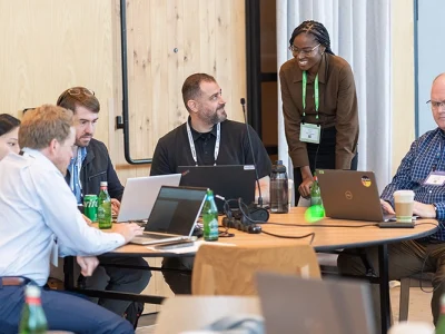 People siting on a table using laptops at Benchmark Gensuite's conference